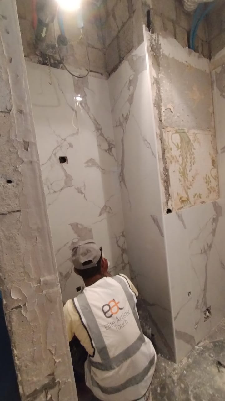 Person working on a construction or renovation project in a room with unfinished walls.