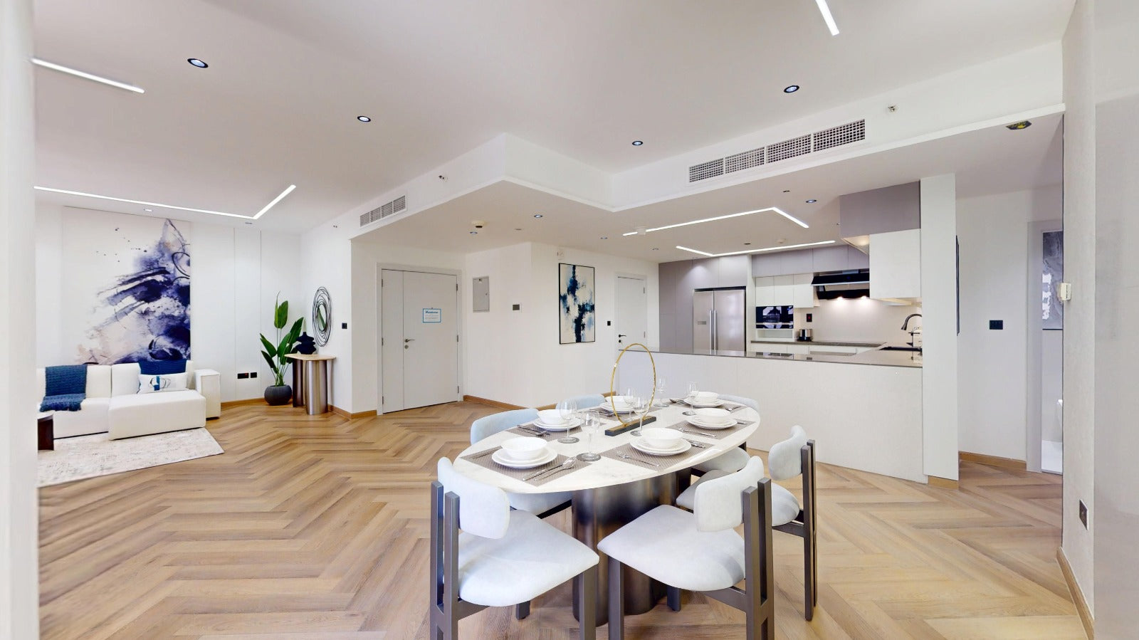 Modern kitchen and dining area with wooden flooring and white walls.