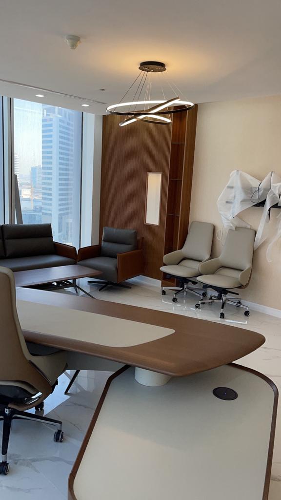 Modern office interior with a large desk, chairs, and large windows.