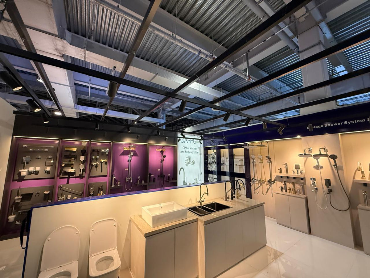 Bathroom showroom with various fixtures and displays on a metallic ceiling.