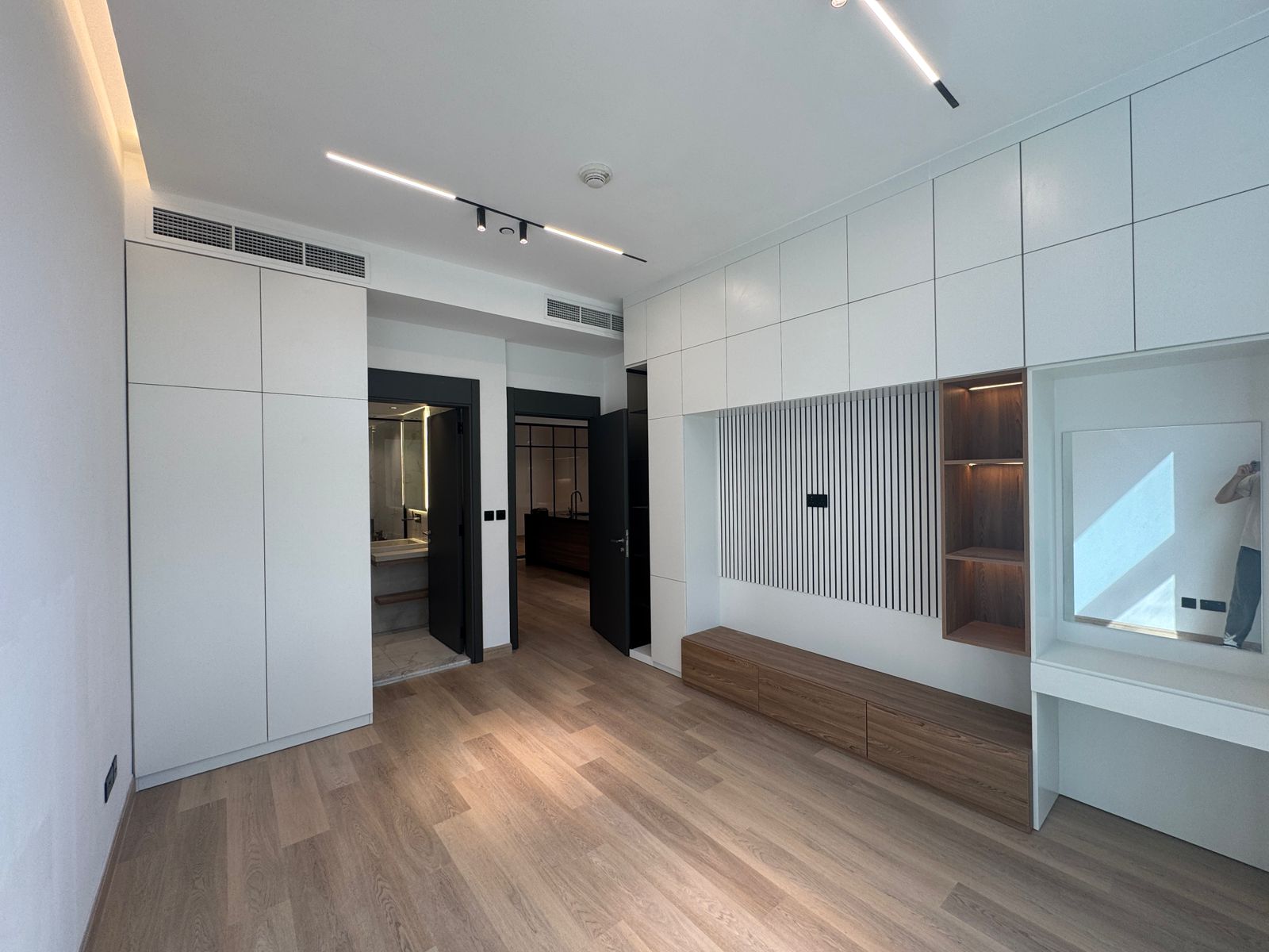 Modern interior of a room with white walls, wooden floor, and minimal furniture.
