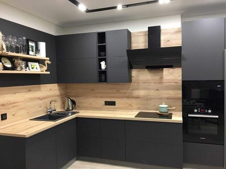 Modern kitchen with black cabinets, wooden countertops, and stainless steel appliances.