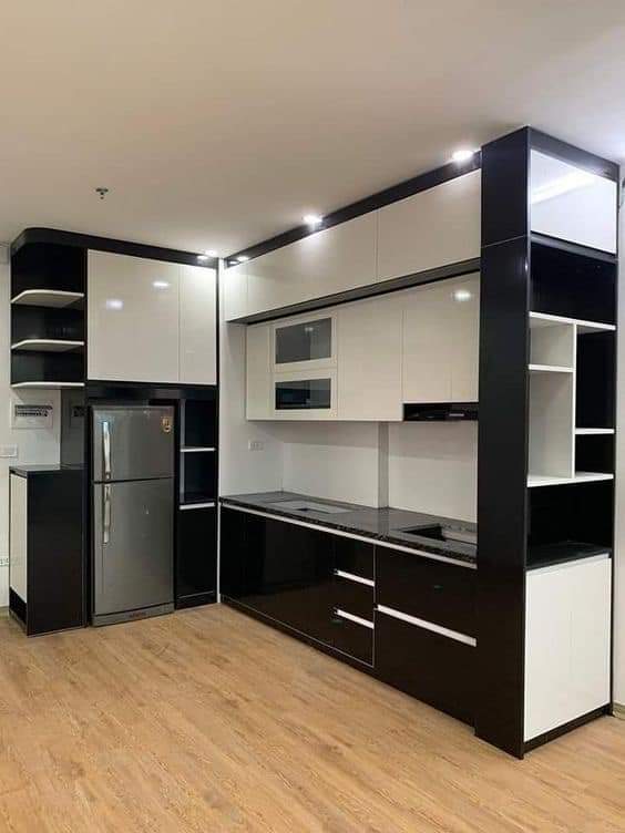 Modern kitchen with black and white cabinets, refrigerator, and appliances.